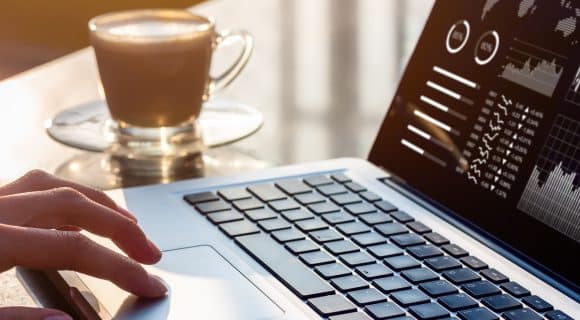Hand on laptop touchpad with analytics dashboard on screen, symbolizing data-driven hotel revenue management strategies.
